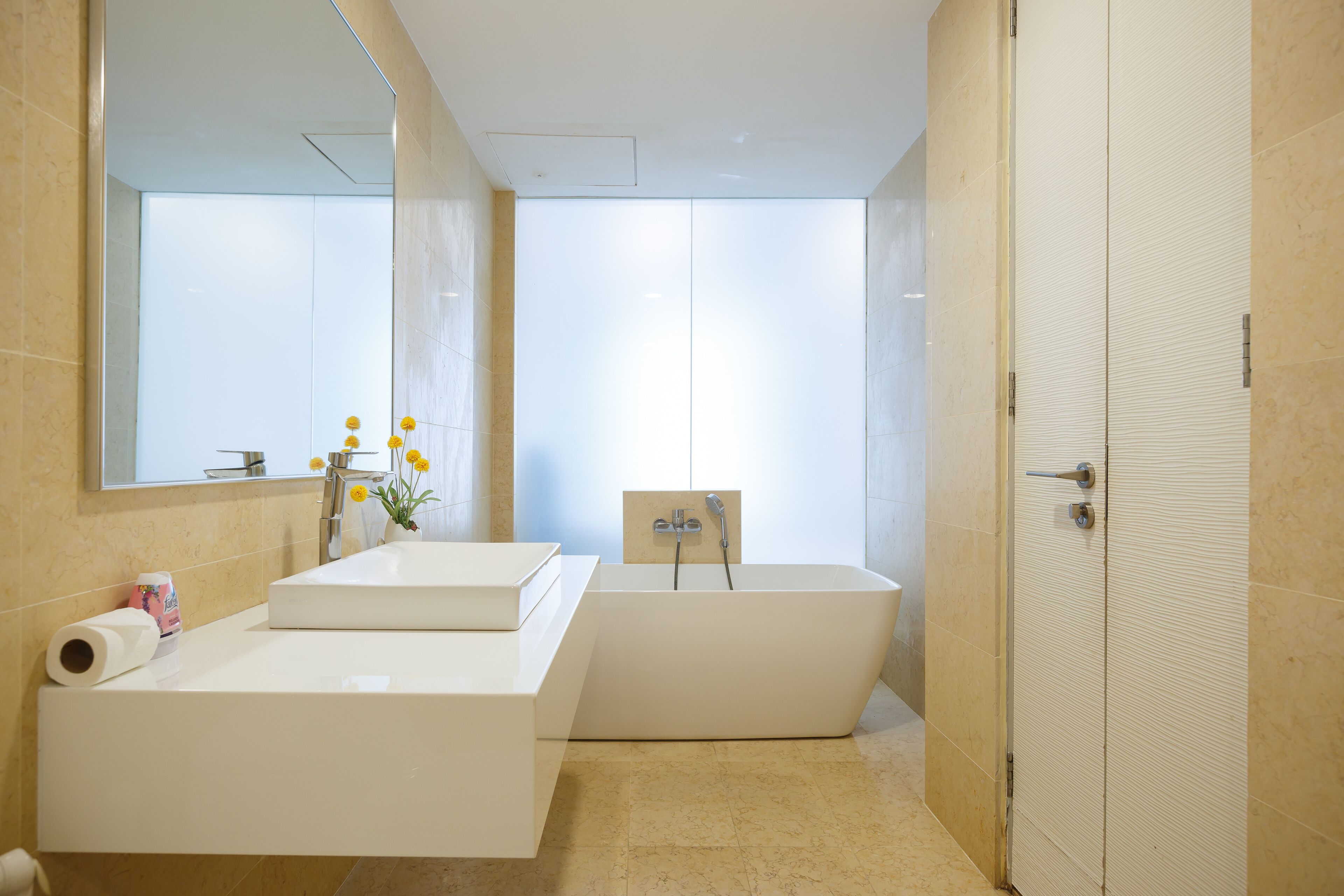 A modern bathroom with a large mirror, a bathtub, and a vanity with a sink.