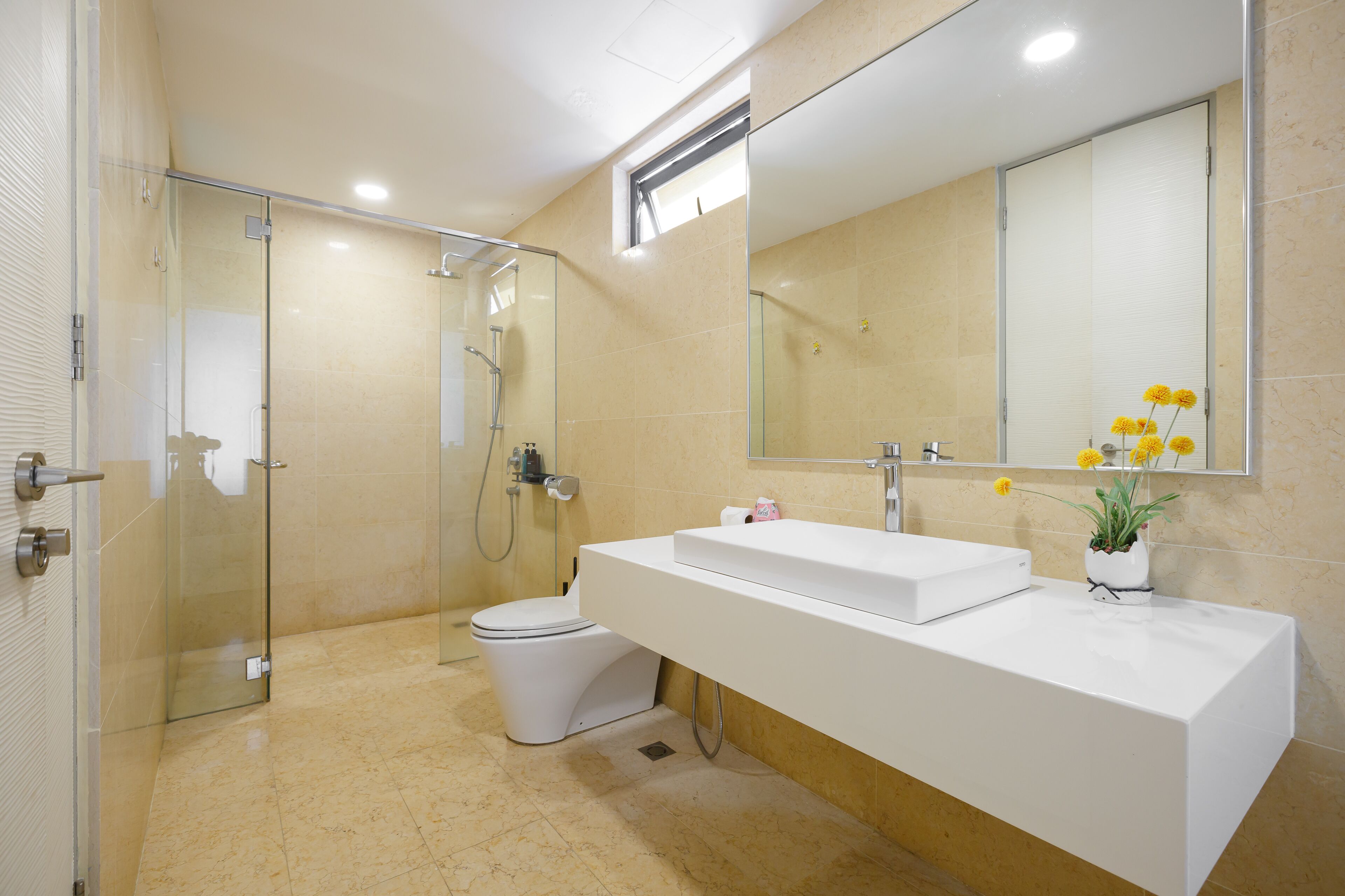 A modern bathroom with a glass-enclosed shower, a white sink, and a toilet.