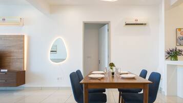 A modern dining area with a wooden table, six blue chairs, and a unique wall-mounted light fixture.