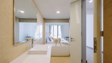 Un baño moderno con un espejo grande, un lavabo blanco y una bañera.