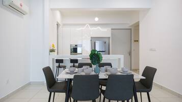 A modern dining area with a white table, black chairs, and a decorative plant.