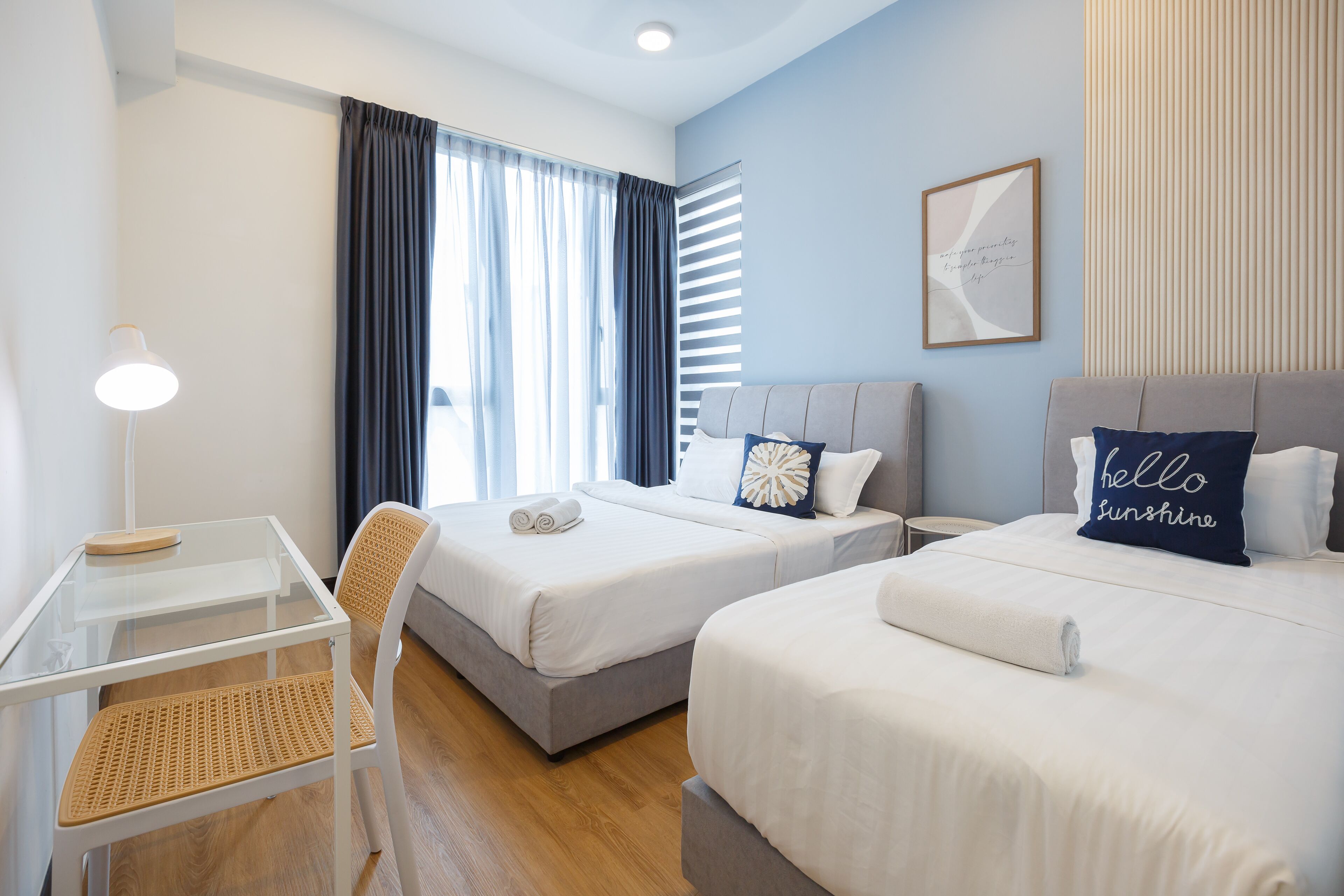 A hotel room with two beds, a glass table, and a chair.