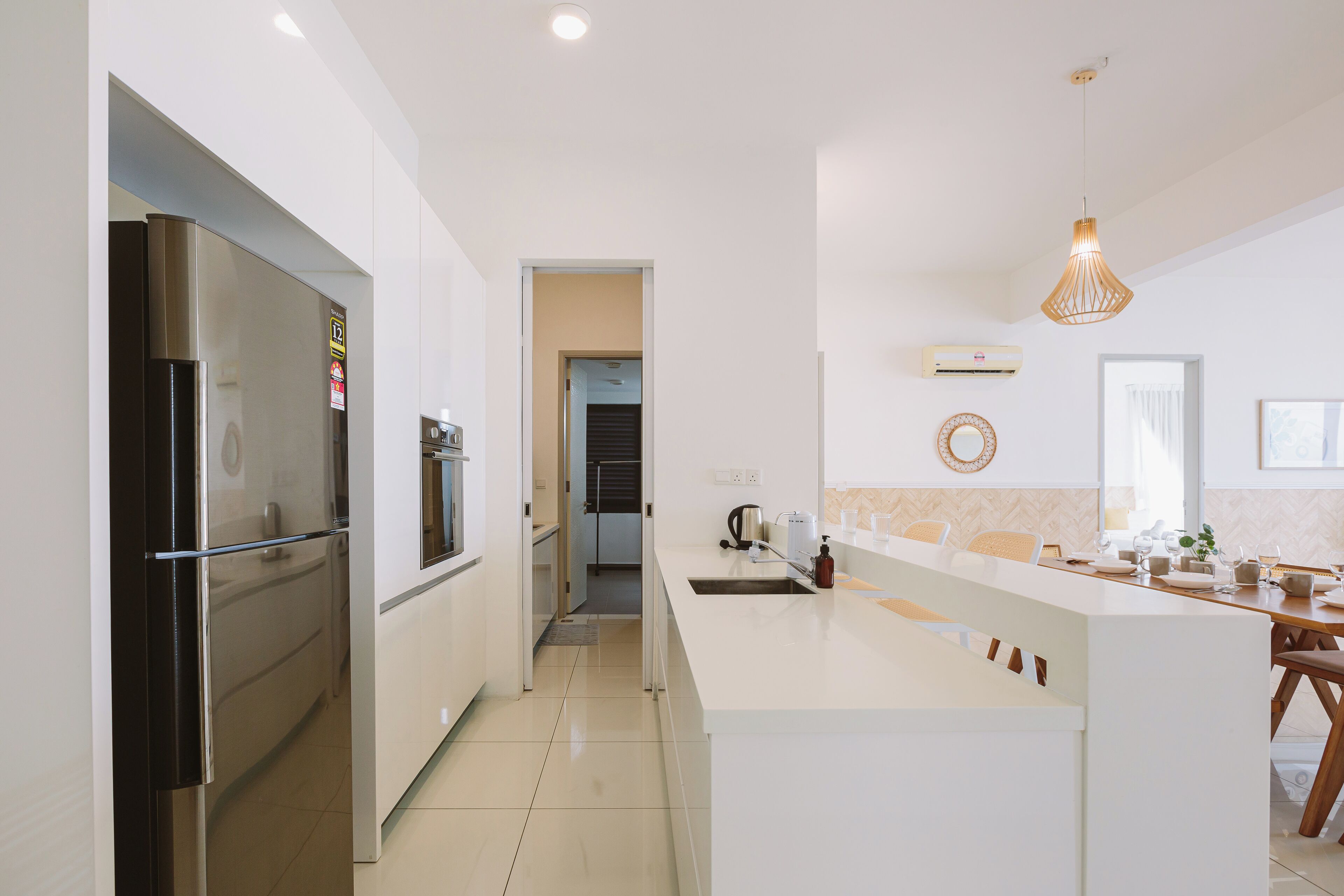 A modern kitchen with a stainless steel refrigerator, a white countertop, and a pendant light.