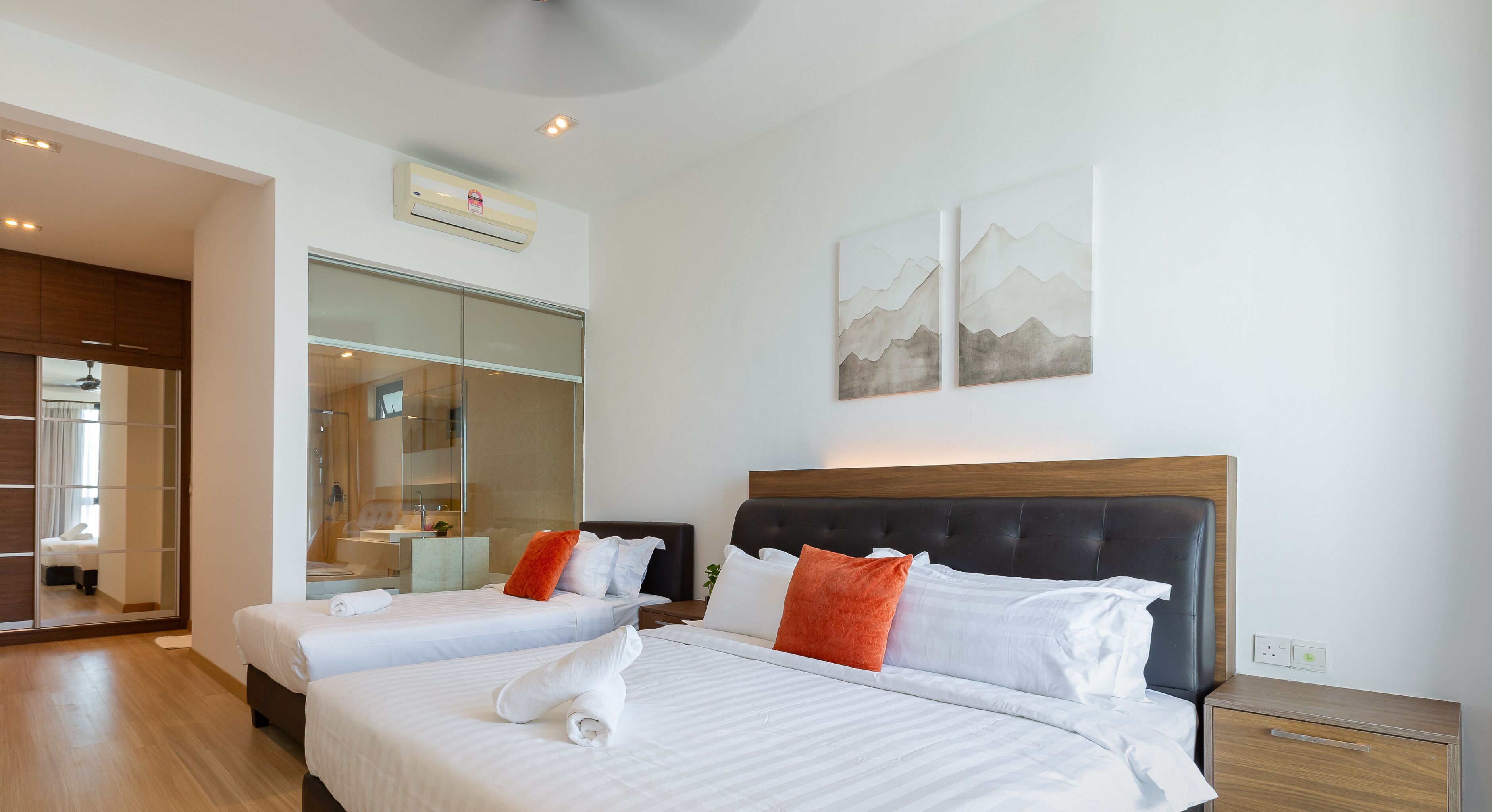 A hotel room with two beds, a large mirror, and artwork on the wall.