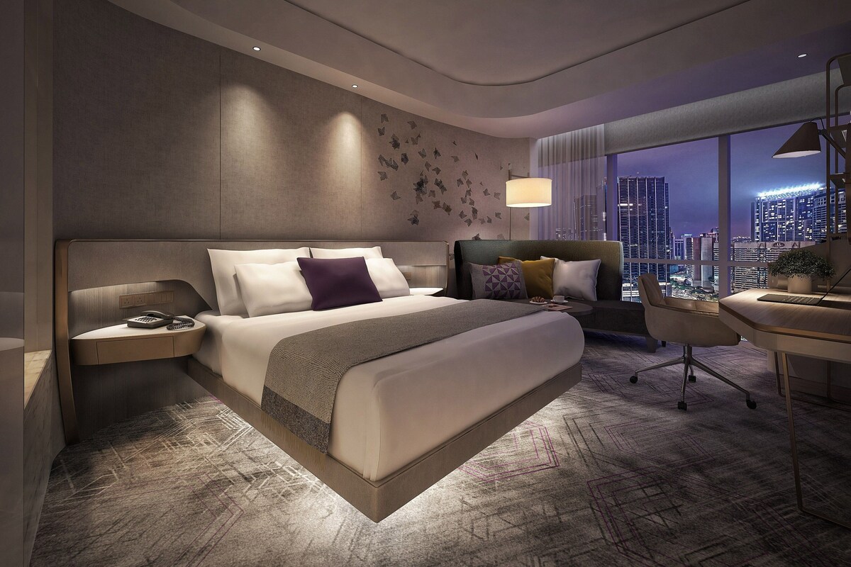 Una habitación de hotel moderna con una cama grande, un escritorio y vistas a la ciudad.