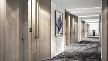 Un pasillo de hotel con paneles de madera, obras de arte enmarcadas y una alfombra estampada.