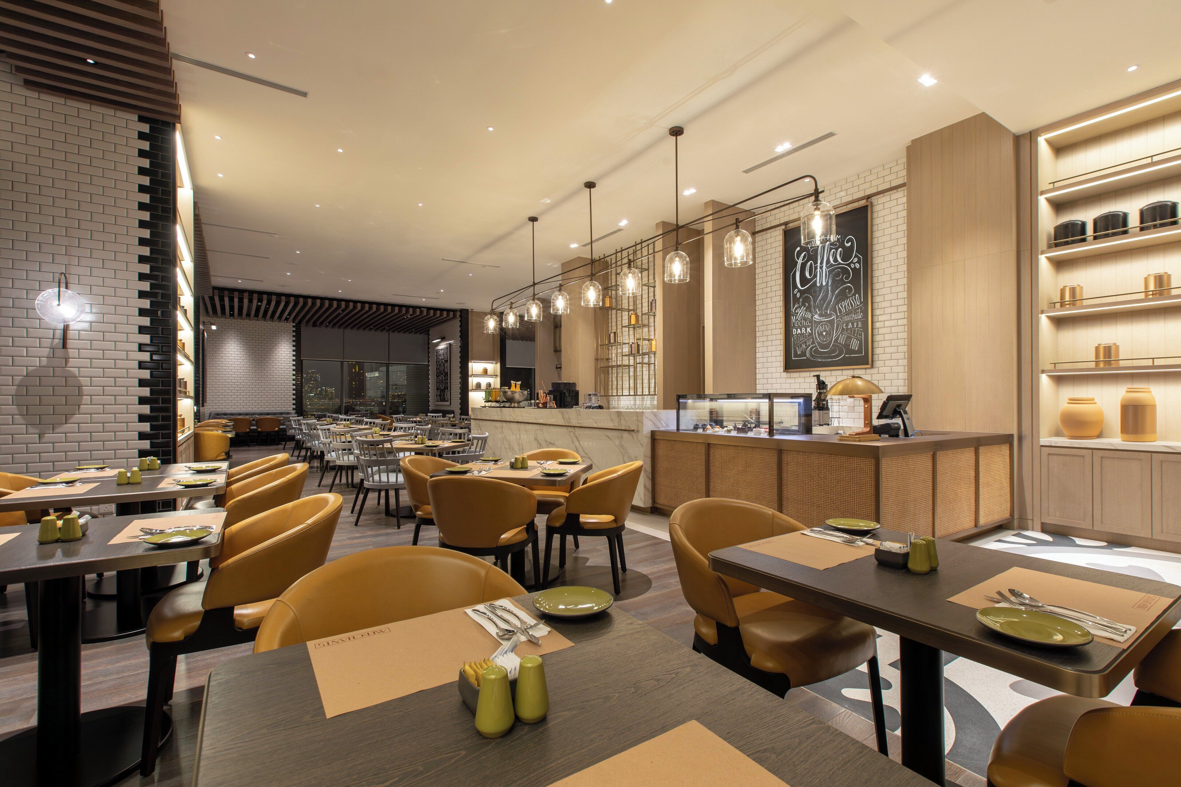 Un restaurant modern amb diverses sales de dinar, incloent-hi una barra i una zona de seients informal.