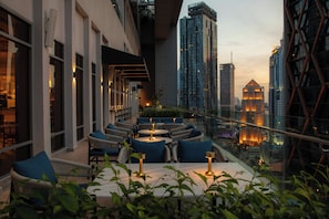 Una terraza en la azotea con mobiliario exterior y vista panorámica de la ciudad.