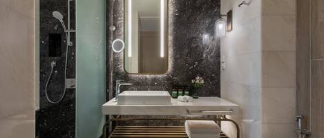 A modern bathroom with a large mirror, a sink, and a shower.