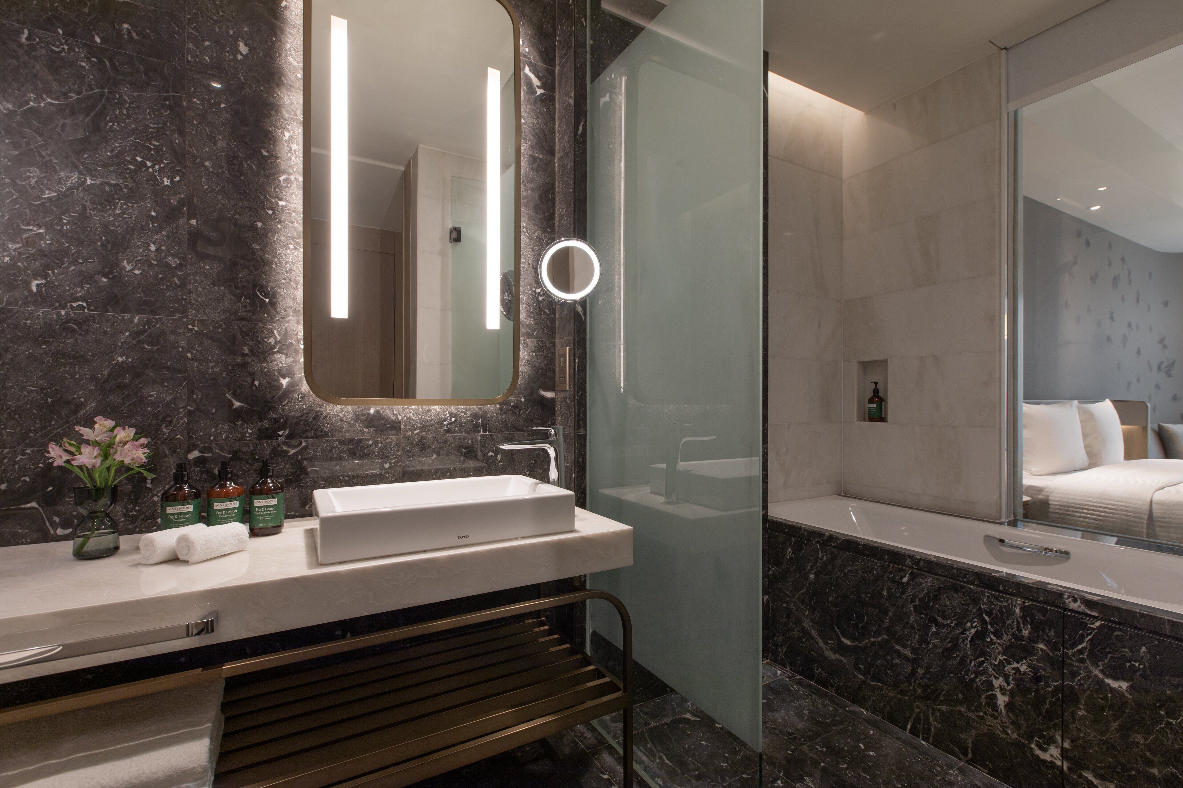 A modern bathroom with a marble sink, a glass shower enclosure, and a large mirror.