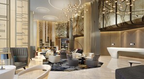 A modern lobby with seating arrangements, a reception desk, and a large chandelier.