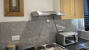 Een keuken met een inbouwafzuigkap, een broodrooster en houten kastjes.