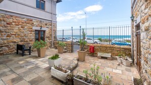 A stone building with a patio area featuring potted plants and a bench.