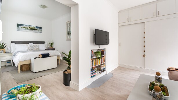 A modern bedroom with a bed, bedside table, and a TV mounted on the wall.