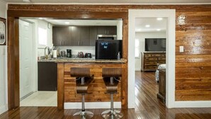 Eine Küche mit Holzbarhocker, einem Kühlschrank und einem Essbereich mit einer Holzwand.
