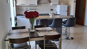 Una cocina moderna con armarios blancos, una isla central y un comedor con sillas y una mesa.