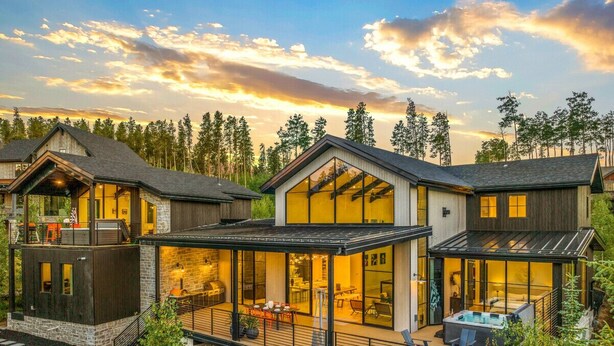 Una casa moderna de varios pisos con terraza, ventanas amplias y un jacuzzi.