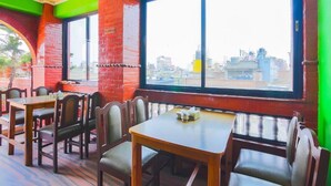 A restaurant with brick walls, large windows, and wooden tables and chairs.
