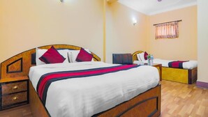 A hotel room with a wooden bed, a nightstand, a bedside table, and a window with curtains.