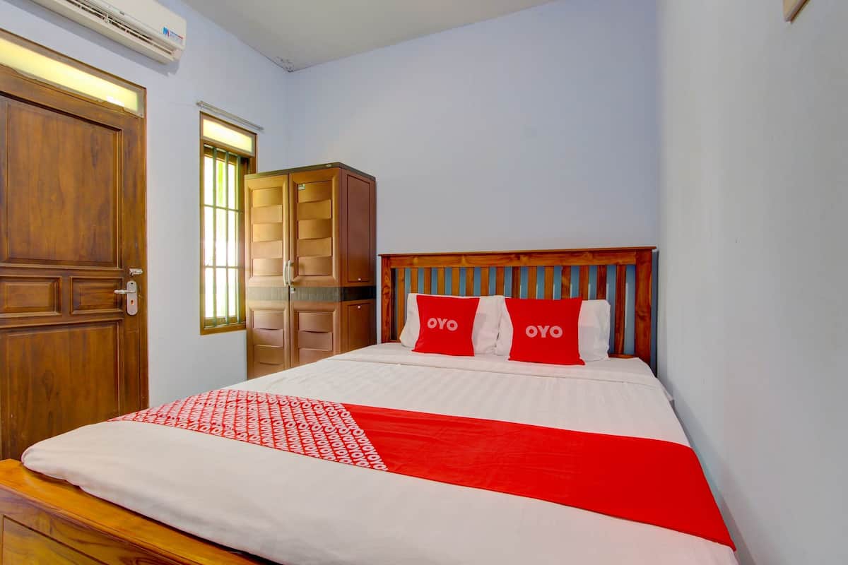 A hotel room with a wooden bed, a wardrobe, and a window with blinds.