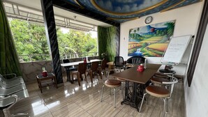 A conference room with a large table, chairs, a whiteboard, and a painting of a landscape. - Hotel O Batodupi Guesthouse Syariah Near Buttu Kasambi (Makassar)