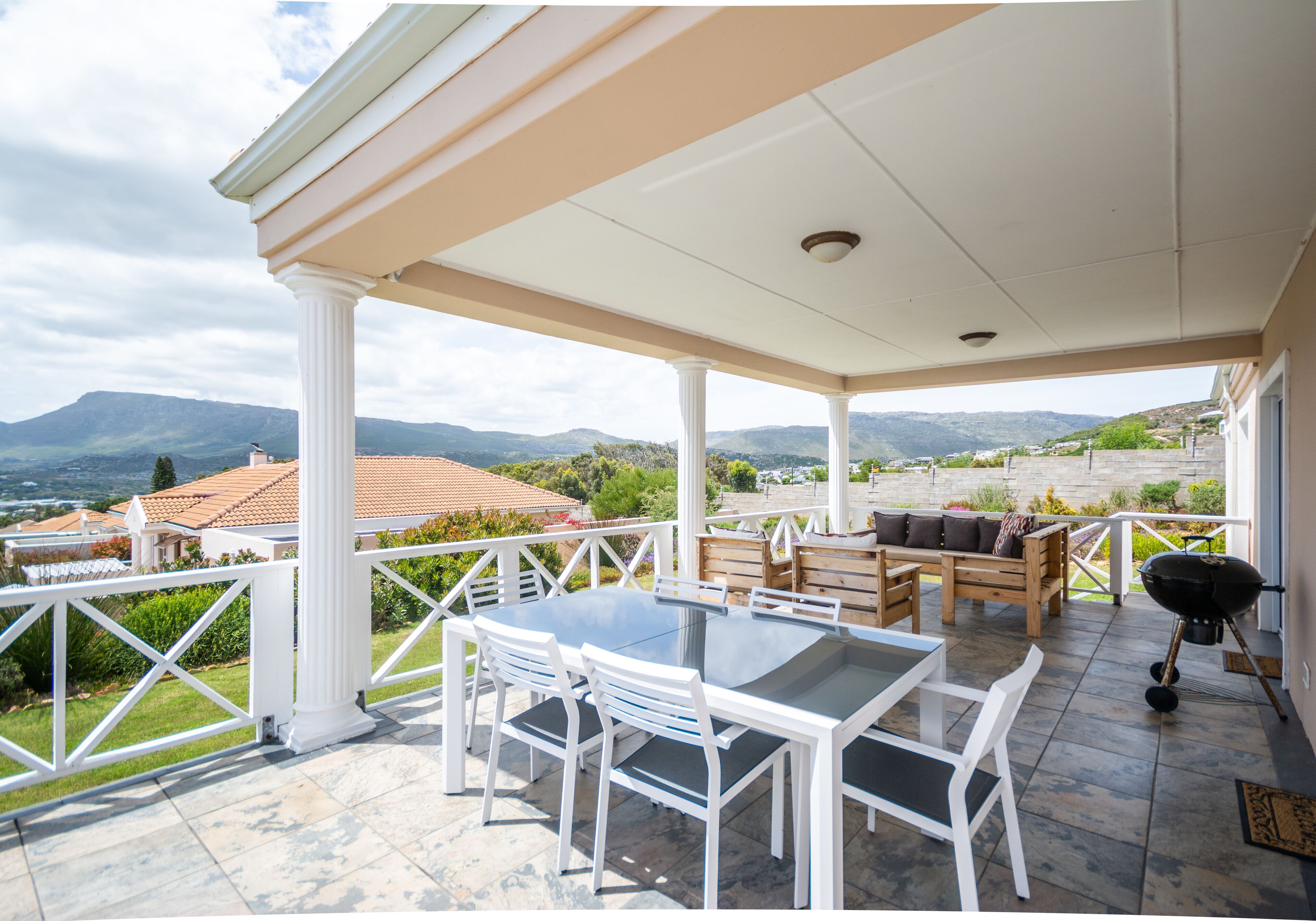 An outdoor patio with a table and chairs, a grill, and a view of the surrounding landscape.