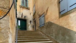Una stretta scala conduce a un edificio con una porta verde e una finestra con persiane.