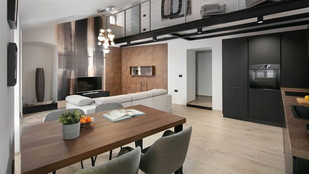 Una cucina moderna con forno integrato e zona pranzo con tavolo e sedie in legno.