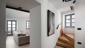 Un interno moderno con un divano grigio, un quadro astratto incorniciato e una scala con gradini in legno.