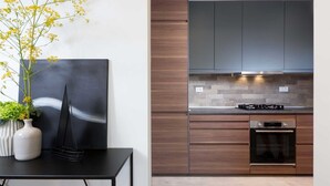 Une cuisine moderne avec des meubles de couleur bois foncé, un plan de travail noir et un four encastré.