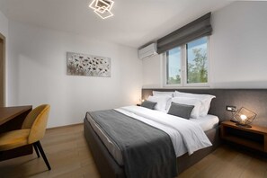 Relax in a serene bedroom with a large bed, wooden nightstand, and desk area.