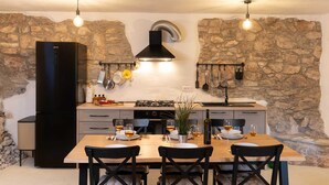 A modern kitchen with stone walls, a black range hood, and pendant lighting. - Casa Dorella in peaceful location with a sea view (Viškovići)
