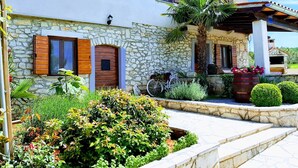 A stone house with a garden, a bicycle, and a palm tree. - Casa Ivanovac with pool and large front yard (Rogočana)