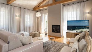 Ein modernes Wohnzimmer mit Kamin, Fernseher und Meerblick.