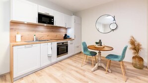Een moderne keuken met witte kastjes, een houten aanrecht en een ronde eettafel met twee stoelen.