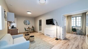 Een moderne woonkamer met een bank, een eethoek, een televisie en een open haard.