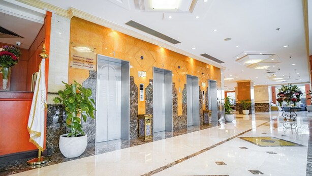 A hotel lobby with a reception desk, elevators, and a marble floor. - EMMAR AL NOOR (Makkah)