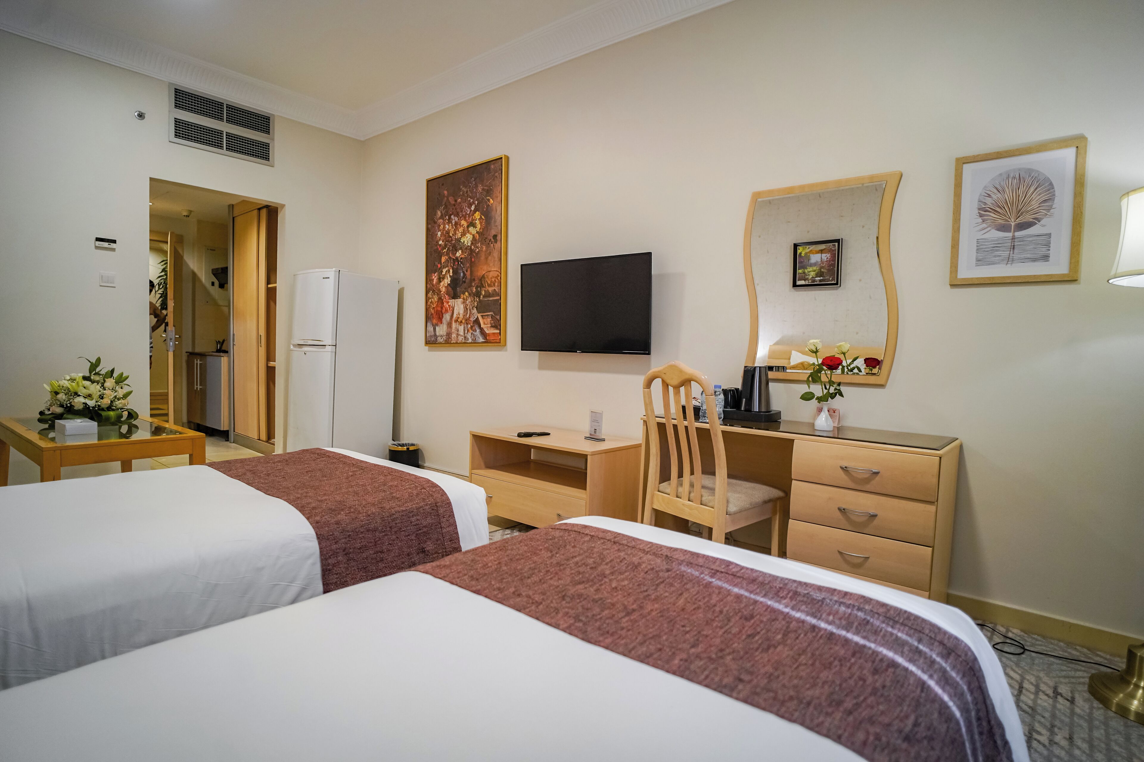 Una habitación de hotel con dos camas, un escritorio, una silla, un televisor y un aparador.