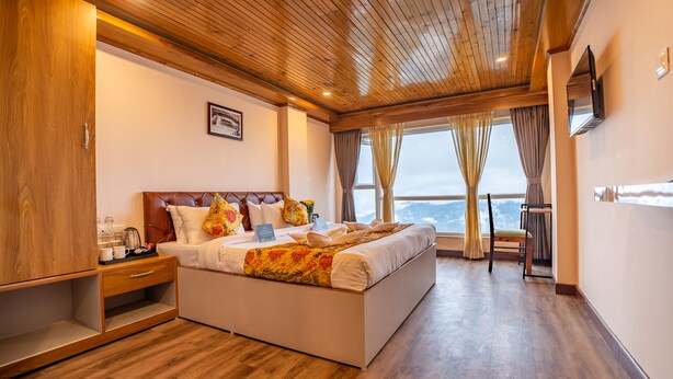 A spacious bedroom with a large bed, wooden ceiling, and a view of the outdoors. - Muscatel Stardust - Chowrasta Mall Road (Darjeeling)