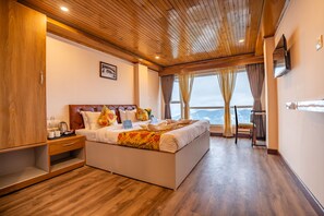 A spacious bedroom with a large bed, wooden ceiling, and a view of the outdoors. - Muscatel Stardust - Chowrasta Mall Road (Darjeeling)