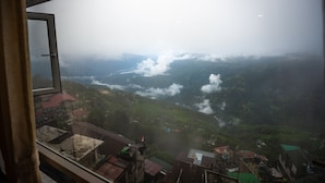 A view from a window overlooking a valley with buildings and greenery. - Muscatel Stardust - Chowrasta Mall Road (Darjeeling)