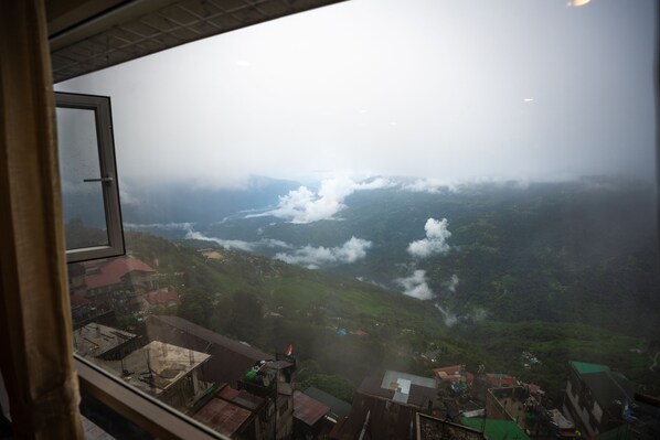 A view from a window overlooking a valley with buildings and greenery. - Muscatel Stardust - Chowrasta Mall Road (Darjeeling)