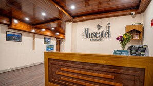A reception desk with a wooden finish, a sign reading "Muscatel Stardust," and a travel desk with brochures. - Muscatel Stardust - Chowrasta Mall Road (Darjeeling)