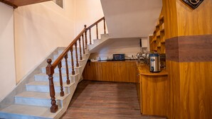 A staircase leading to a kitchen area with wooden cabinets and a coffee maker. - Muscatel Stardust - Chowrasta Mall Road (Darjeeling)