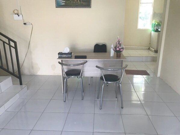 A reception desk with two chairs, a painting above, and a staircase to the left. - SPOT ON 93020 Rumah Singgah Ganjuran (Sumbermulyo)