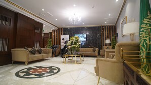 A spacious lobby with a marble floor, a chandelier, and a green flag. - Emaar Andalusia (Makkah)