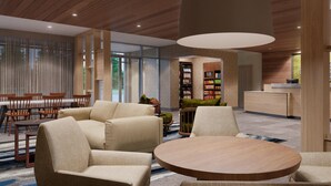 Un lobby moderno con una mesa redonda de madera, sofás color beige y una estantería.