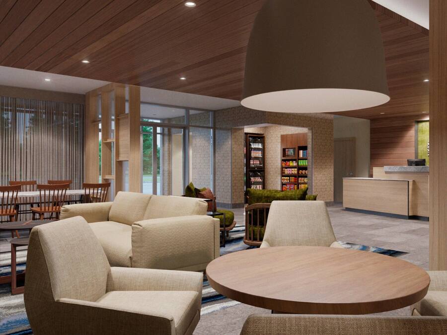Una hall moderna con un tavolo rotondo in legno, divani beige e una libreria.