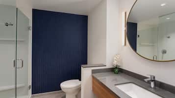 Un baño moderno con cabina de ducha de vidrio, inodoro blanco y tocador con espejo.