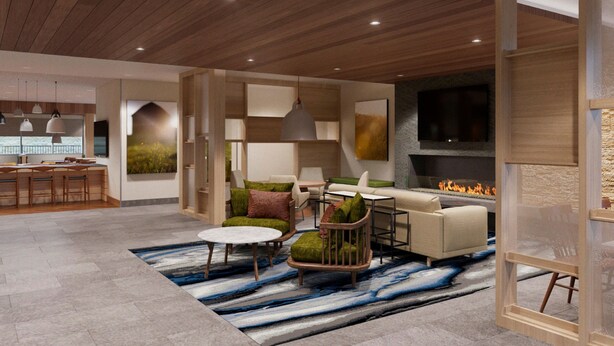Una sala de estar moderna con chimenea, asientos cómodos y una cocina visible a través de un ventanal.
